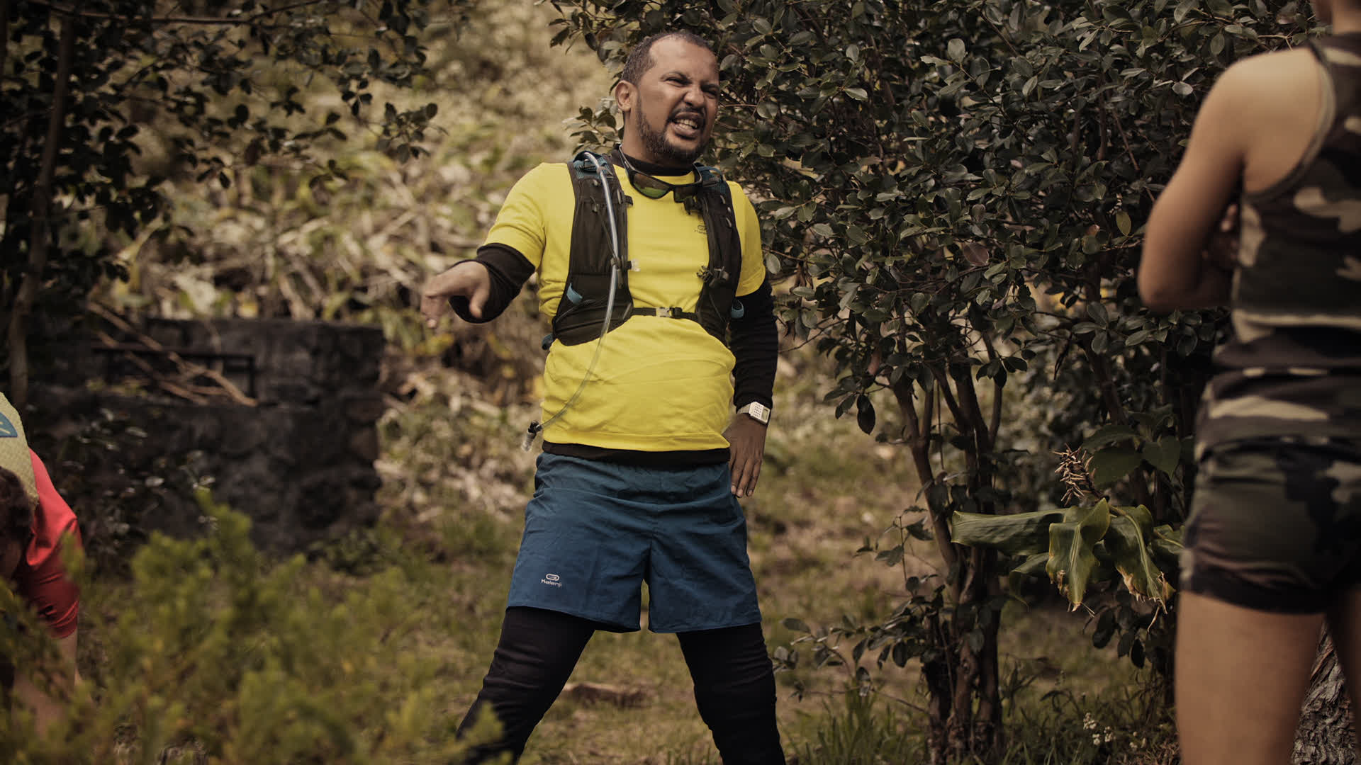 Un homme en tenue de randonnée jaune et bleu dans un environnement naturel.