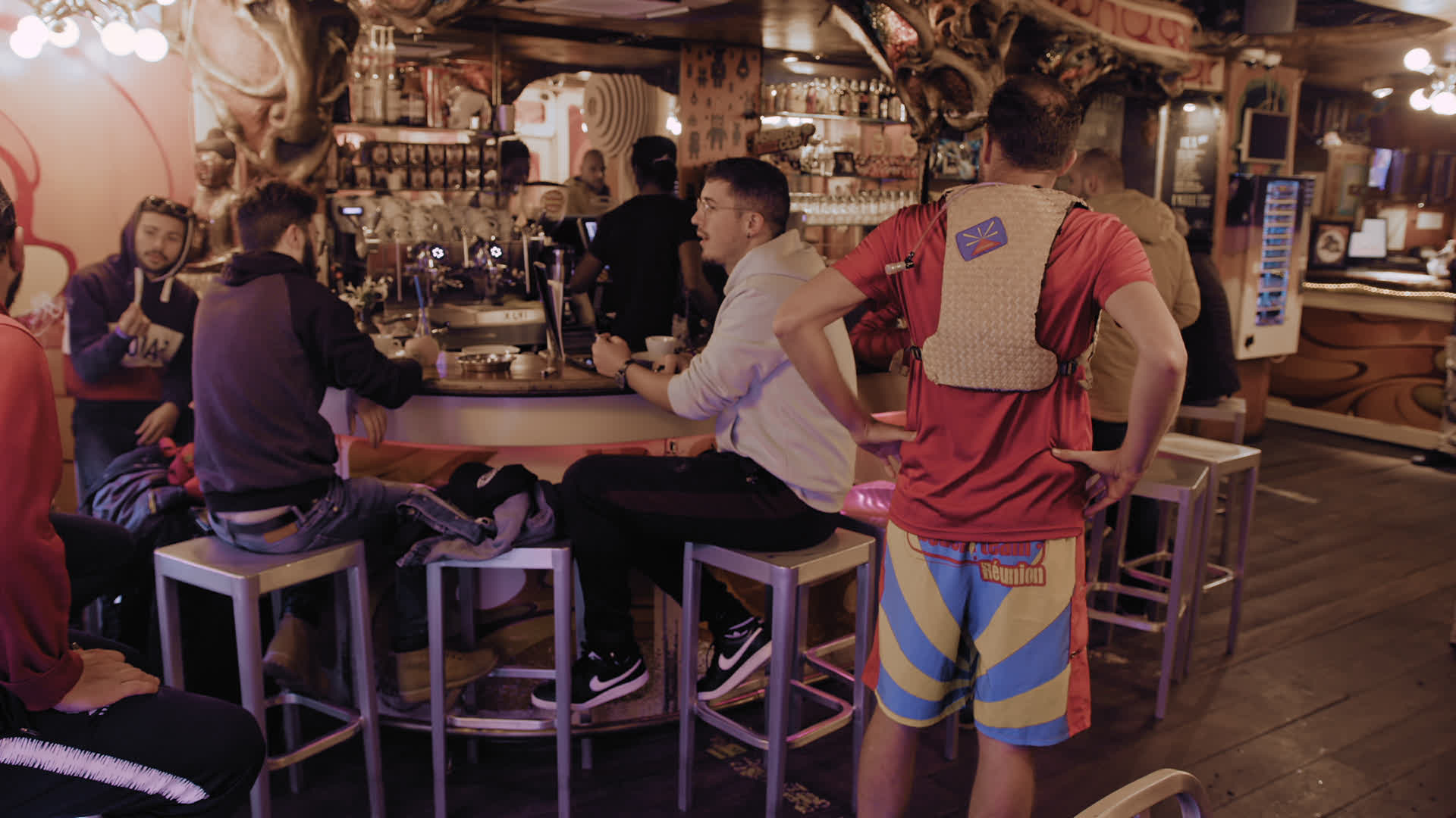 Professional bar scene featuring people and a bartender in a cozy café atmosphere with 'Réunion' short.